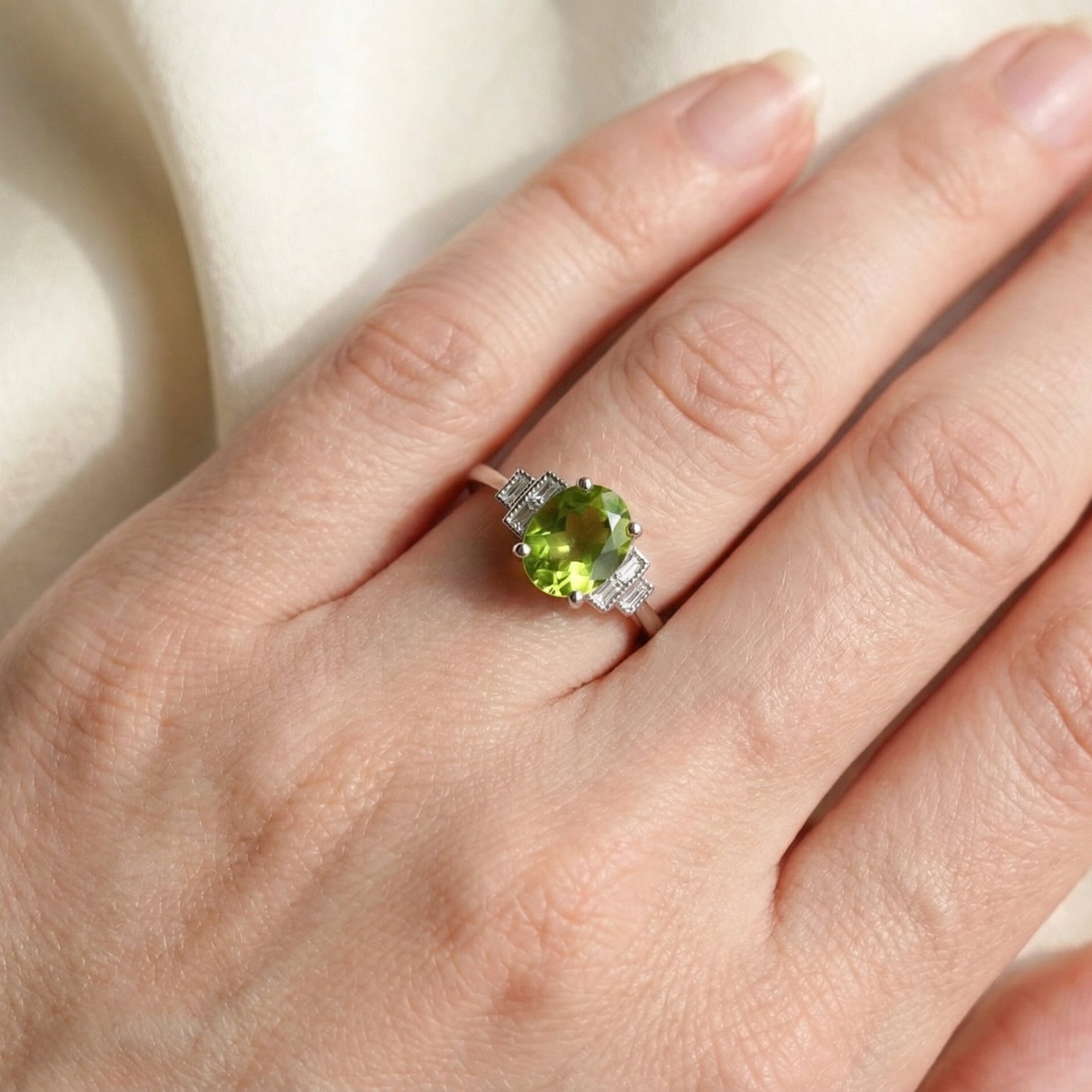 hand A fine gem set ring featuring a vibrant lime-green oval faceted peridot,