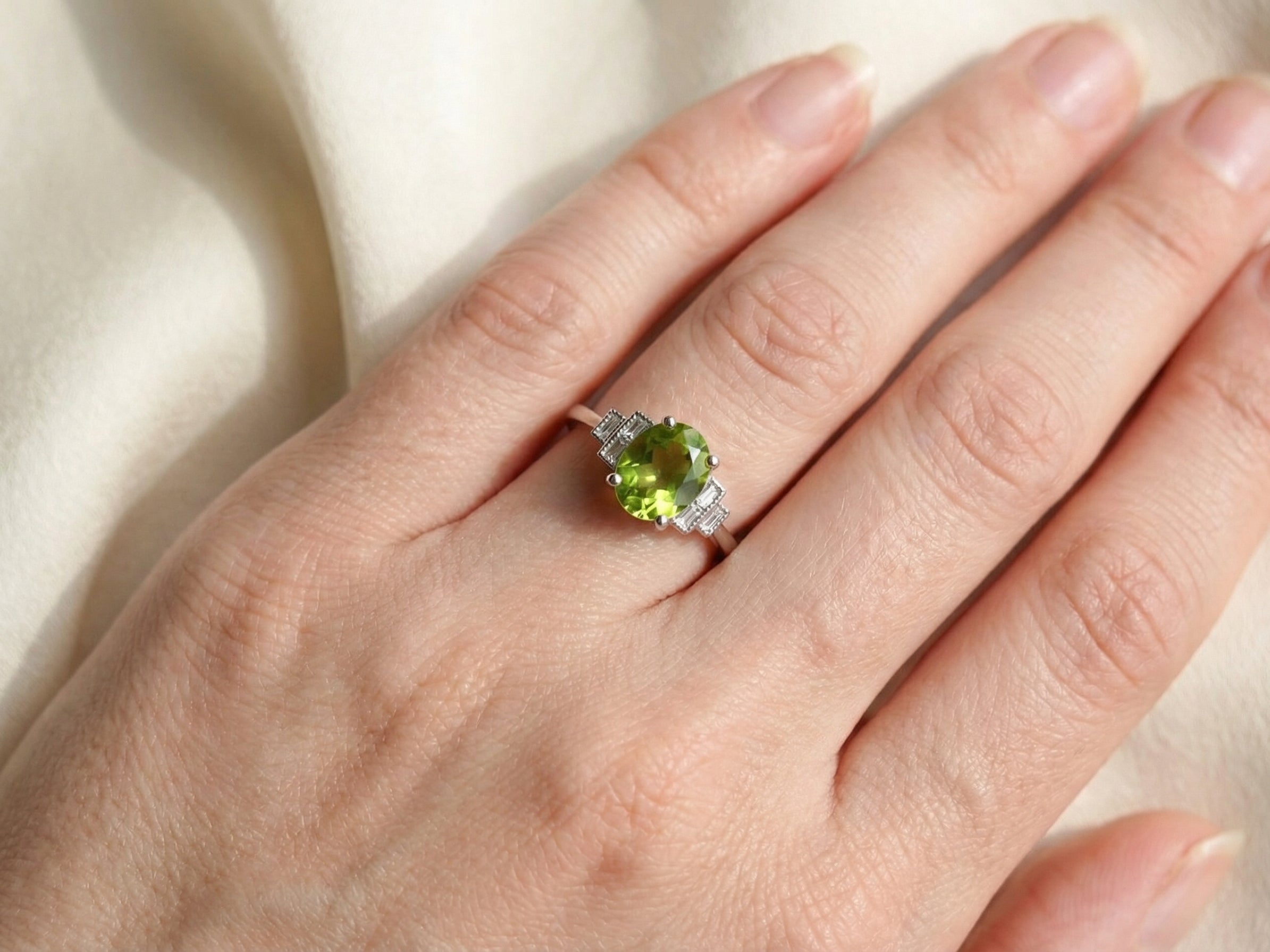hand A fine gem set ring featuring a vibrant lime-green oval faceted peridot,