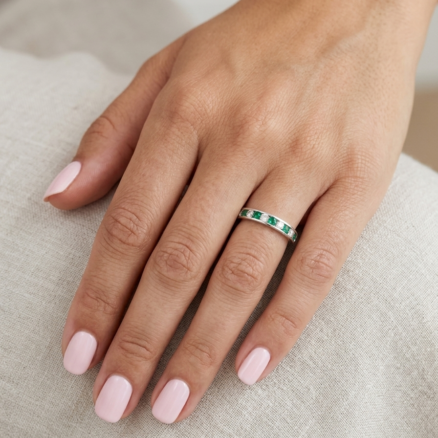 hand A fine platinum half hoop eternity ring. This is a new ring*. Channel set gem stones, five bright green emeralds 2.6mm each (0.54 carats total)