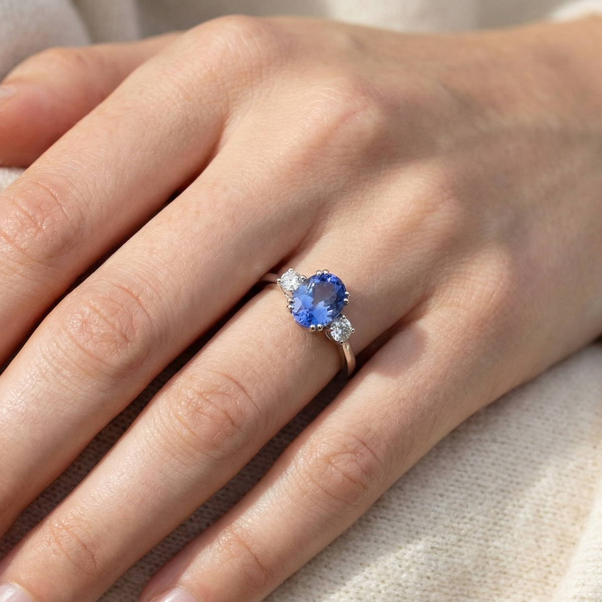 hand A fine three stone trilogy ring. The centre stone a 4A tanzanite gem stone, measures 10x8mm (est 3 carats) 