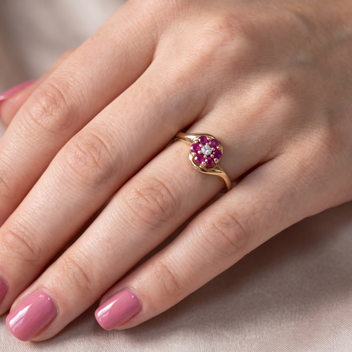 hand A modern 9 carat gold cluster ring. At the centre a small diamond, this complimented by an outer halo of six 2.4mm rubies (each 0.05 carats)