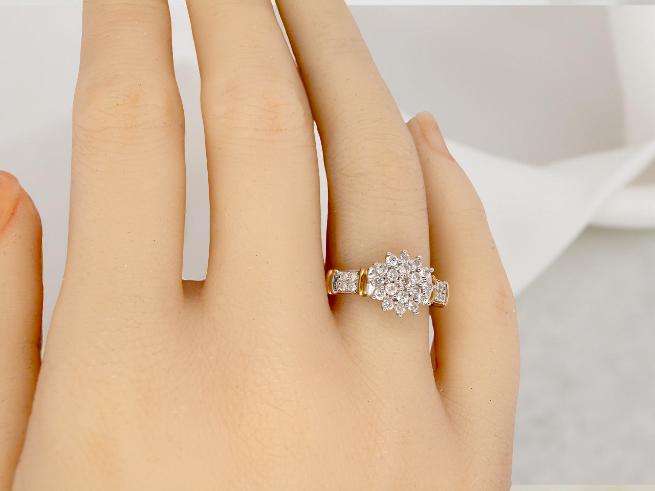 hand A modern 9 carat gold cluster ring featuring a round head fully set with nineteen brilliant-cut white diamonds,