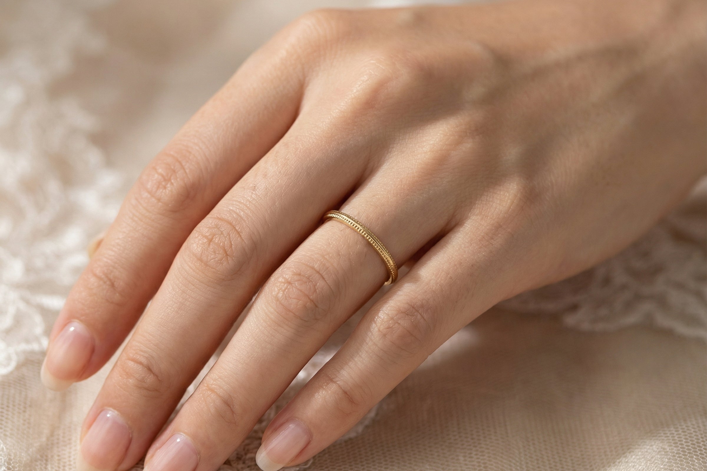 hand A narrow 18 carat gold wedding ring bead pattern