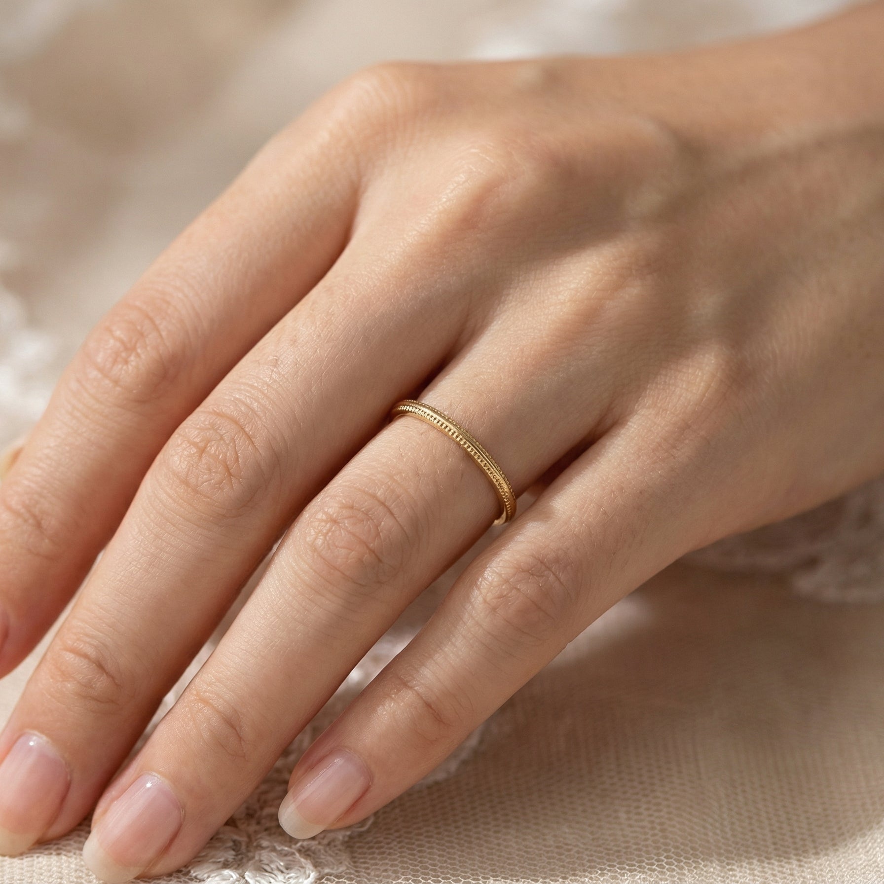hand A narrow 18 carat gold wedding ring bead pattern