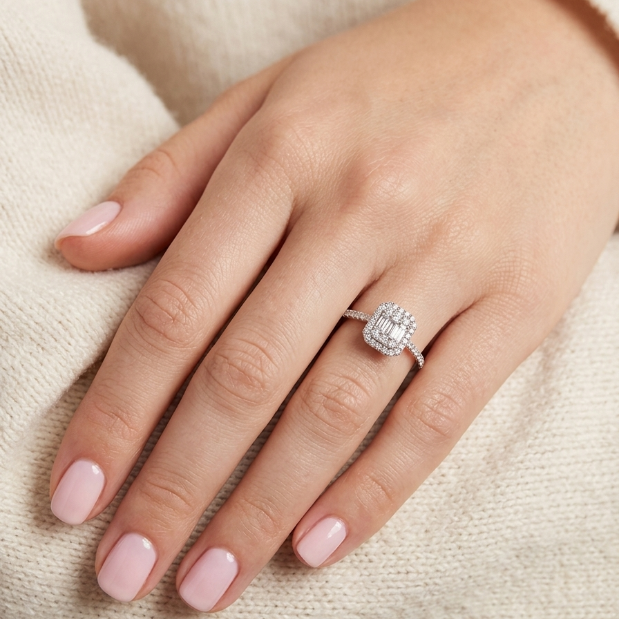 hand A rectangular diamond cluster ring. Centre portion is set with three baguette cut white diamonds 3x1.6mm and six mixed cut diamonds 2mm each.
Surrounded by a halo of twenty two small round diamonds