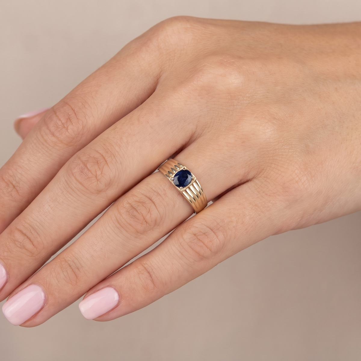 hand A solitaire dress ring that features an oval cut dark blue sapphire, 6x5mm. Wide ribbed patterned shoulders, 7mm width and tapering to a 3.8mm shank at the reverse.