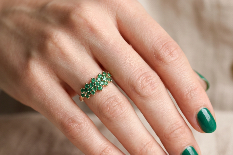hand A striking and unusual dress ring, designed with multiple clusters of round-cut emeralds set beautifully across the finger for a bold, eye-catching look.