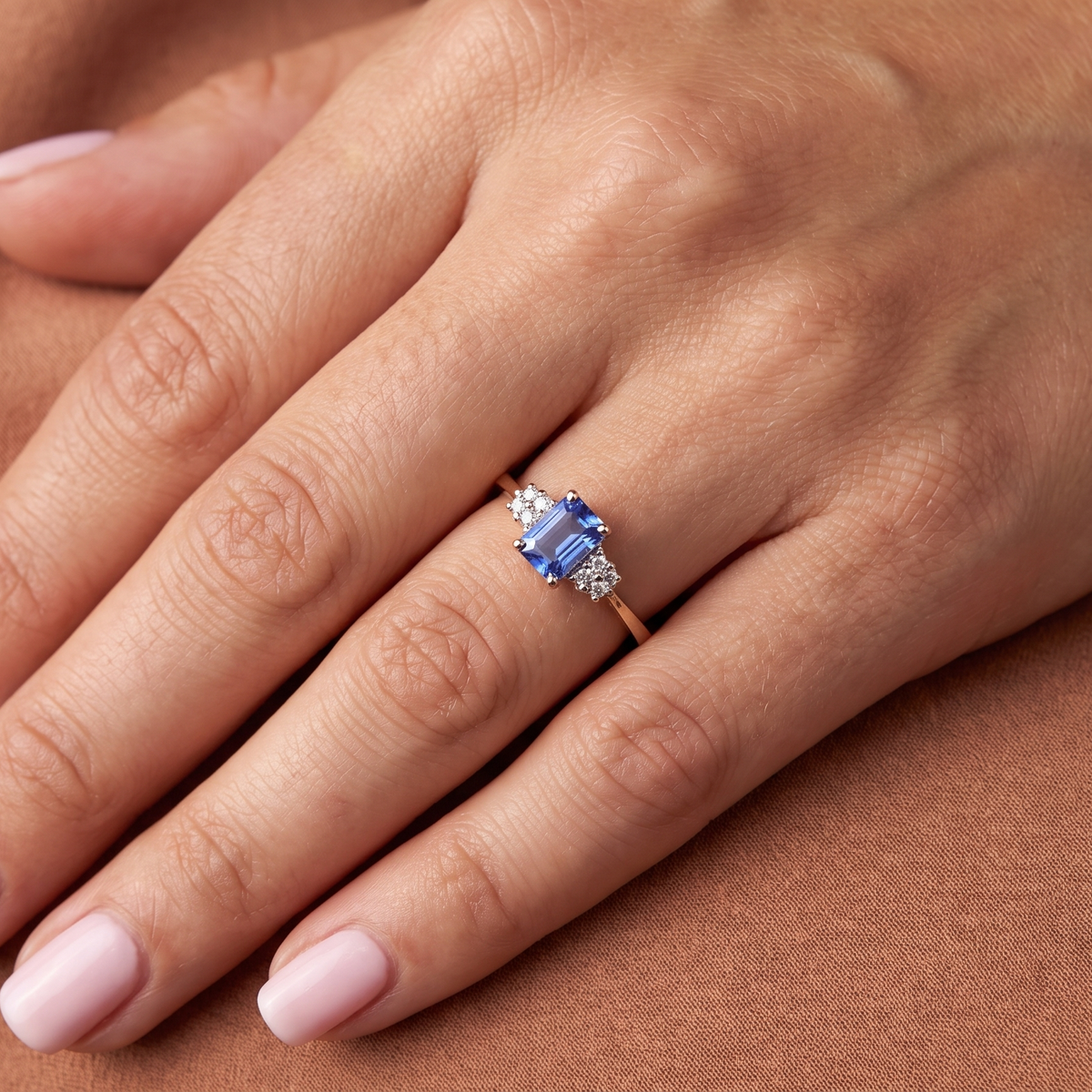 hand A three stone 18 carat gold ring. Features a rectangular tanzanite centre stone 6x4mm (est 0.50 carats)