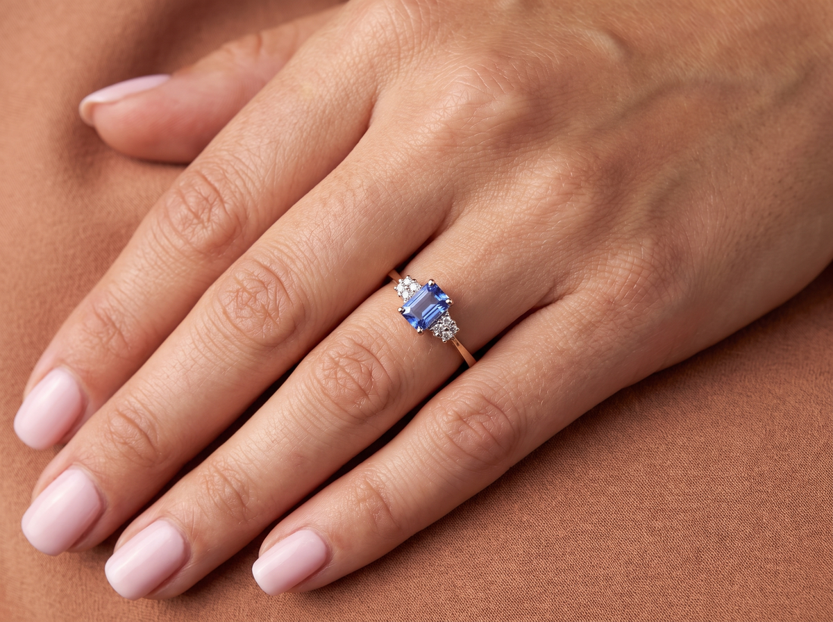 hand A three stone 18 carat gold ring. Features a rectangular tanzanite centre stone 6x4mm (est 0.50 carats)