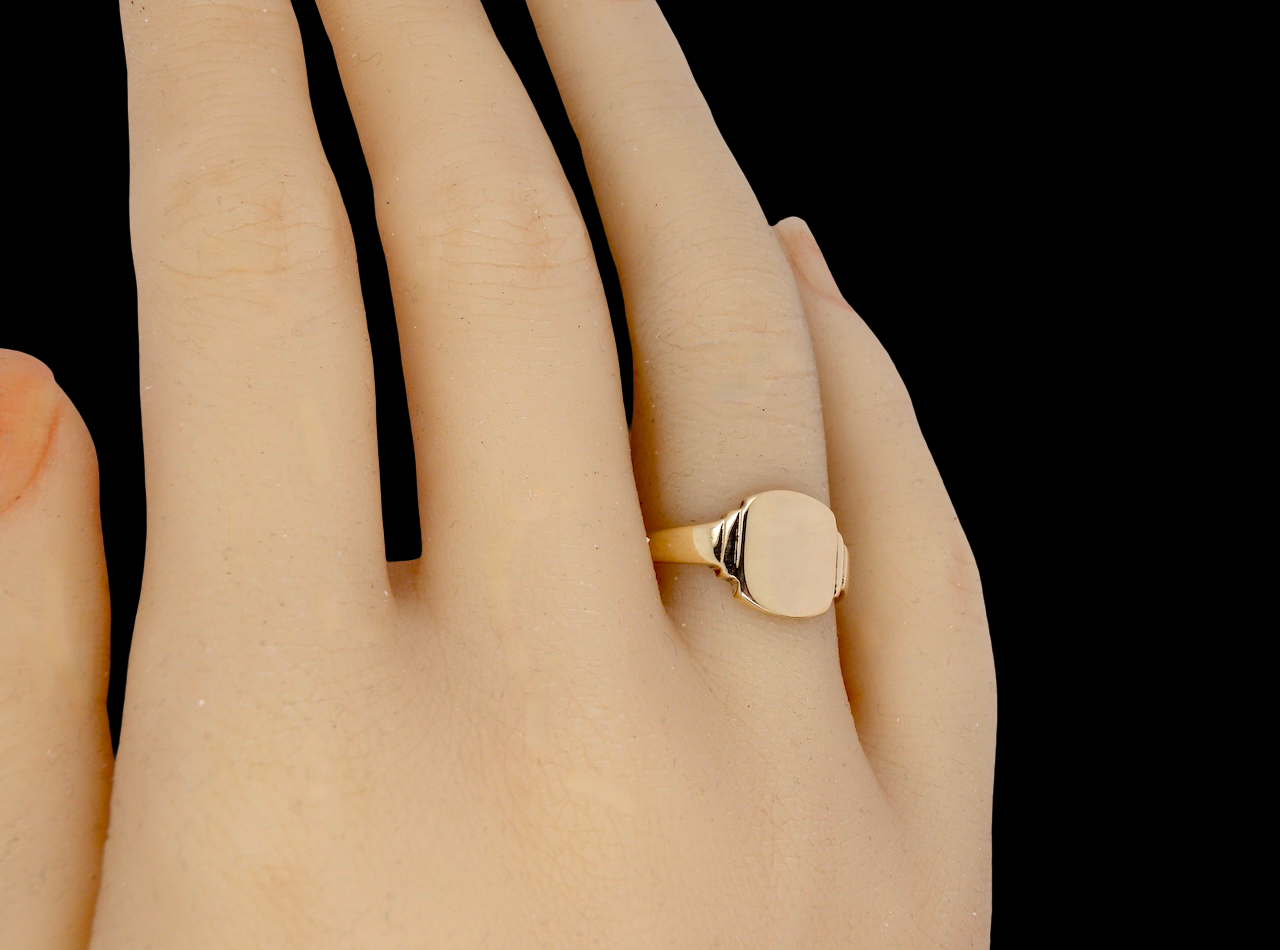 Gold ring on a person's finger against a black background