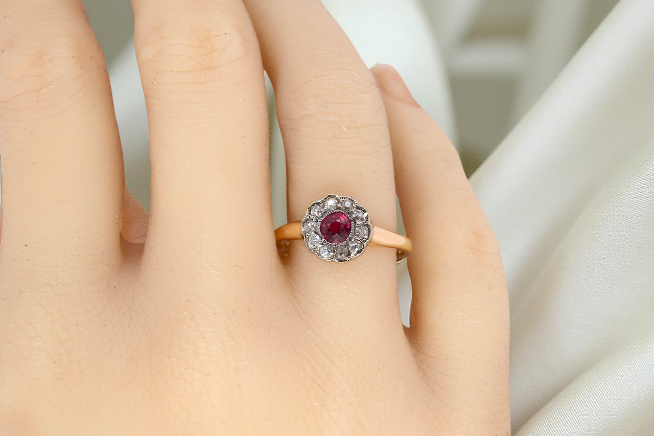 hand A very pretty vintage daisy cluster ring. Features to the centre a round pink red ruby that measures 4mm, and is mille grain set.