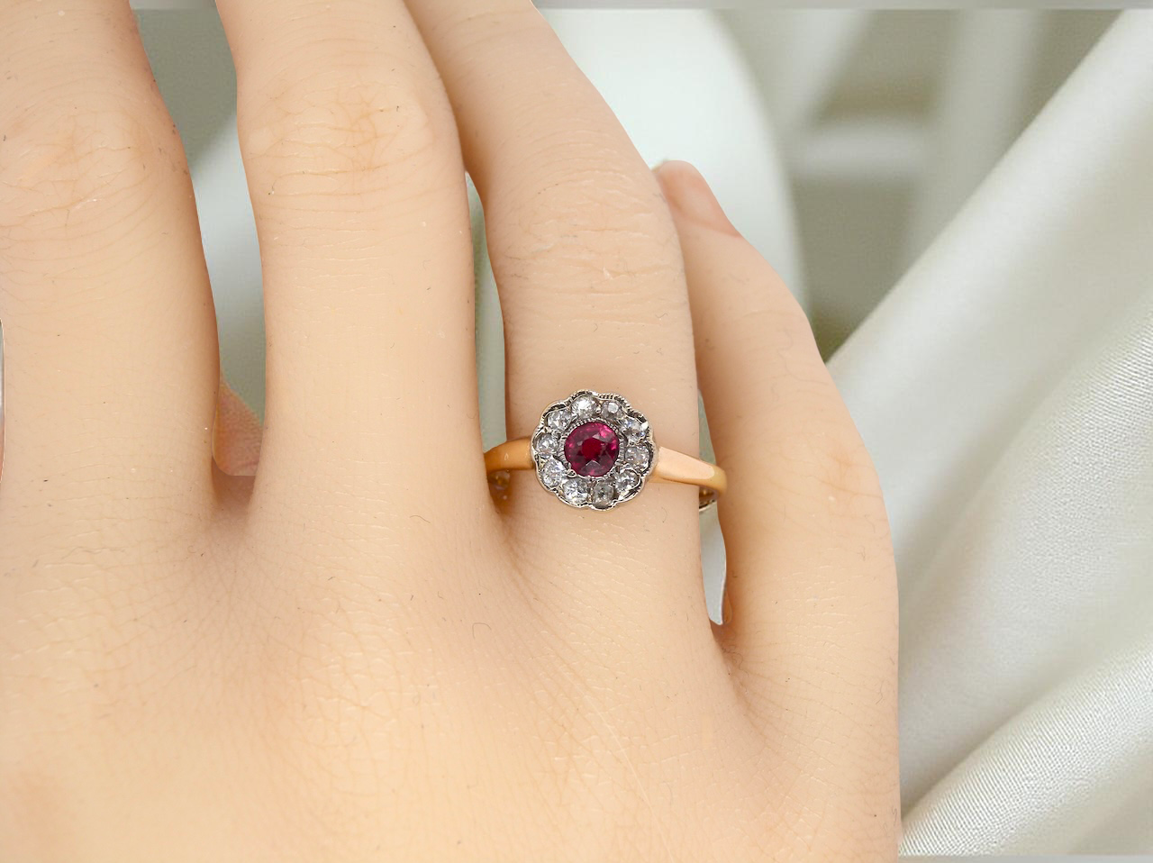 hand A very pretty vintage daisy cluster ring. Features to the centre a round pink red ruby that measures 4mm, and is mille grain set.