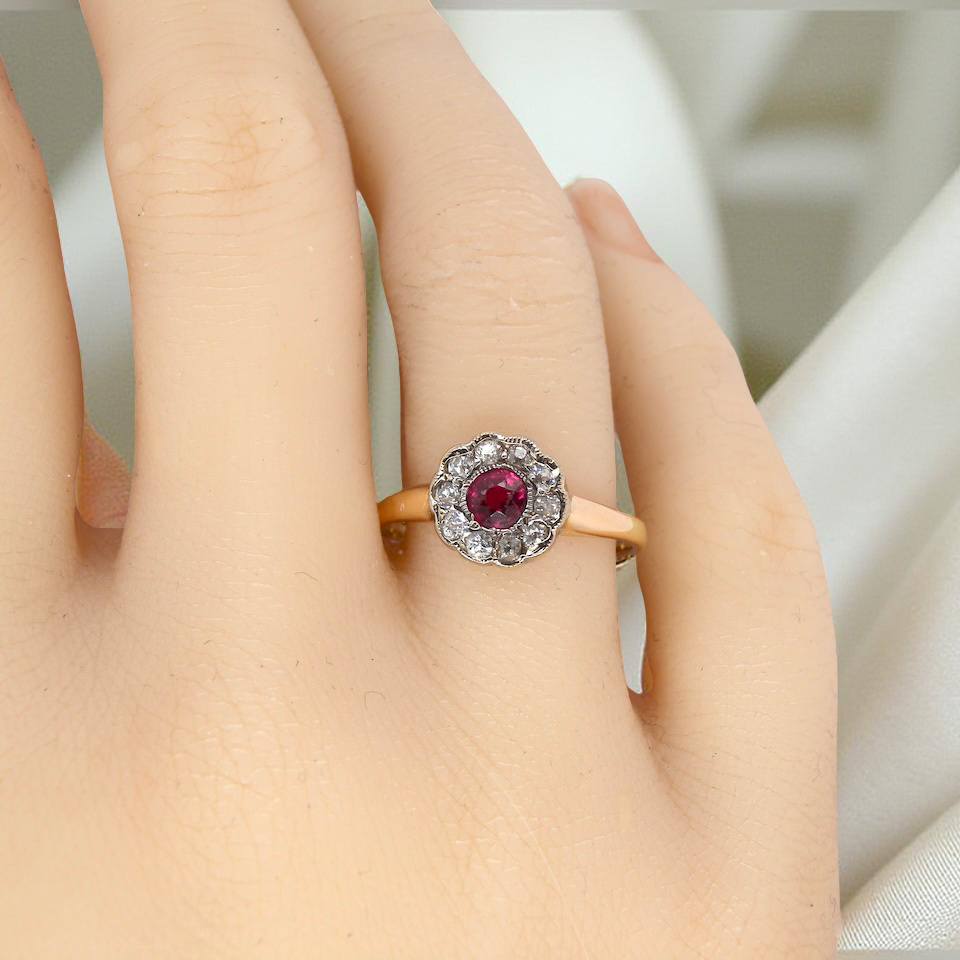 hand A very pretty vintage daisy cluster ring. Features to the centre a round pink red ruby that measures 4mm, and is mille grain set.