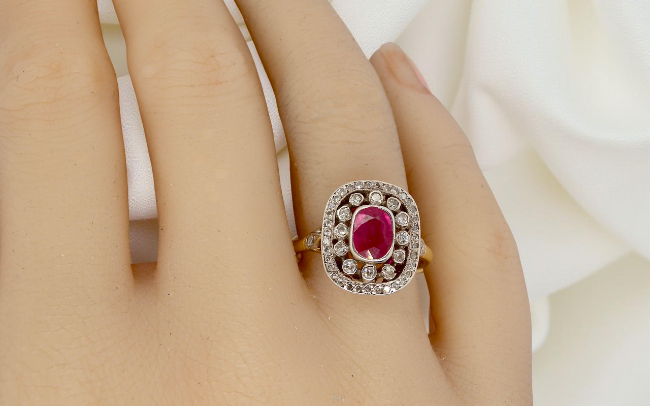 Ruby ring with diamond accents on a hand against a white background