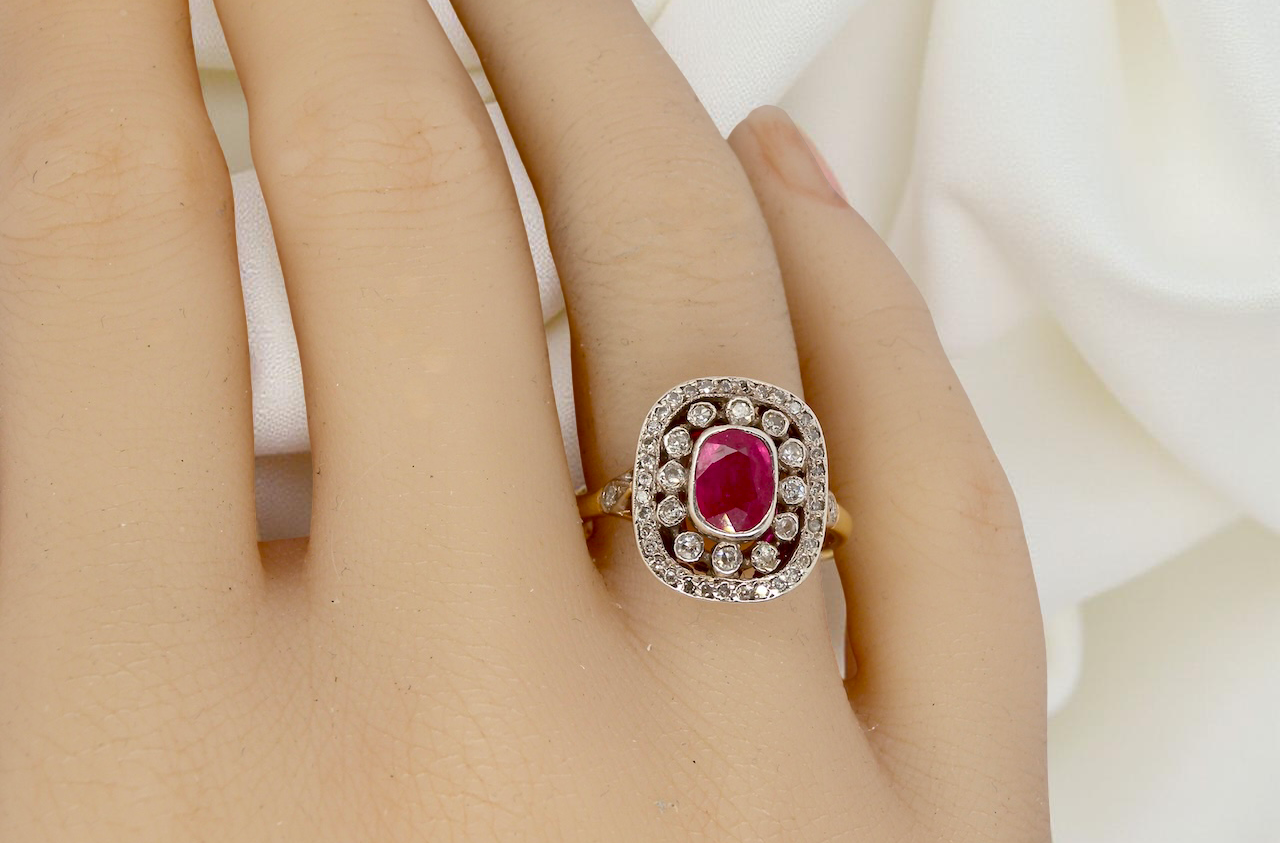 Ruby ring with diamond accents on a hand against a white background
