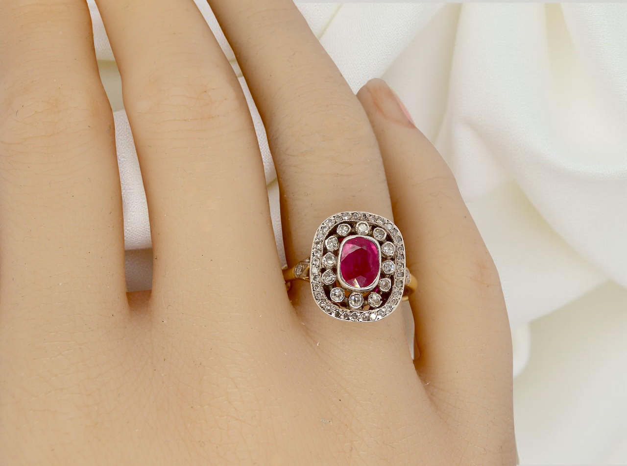 Ruby ring with diamond accents on a hand against a white background