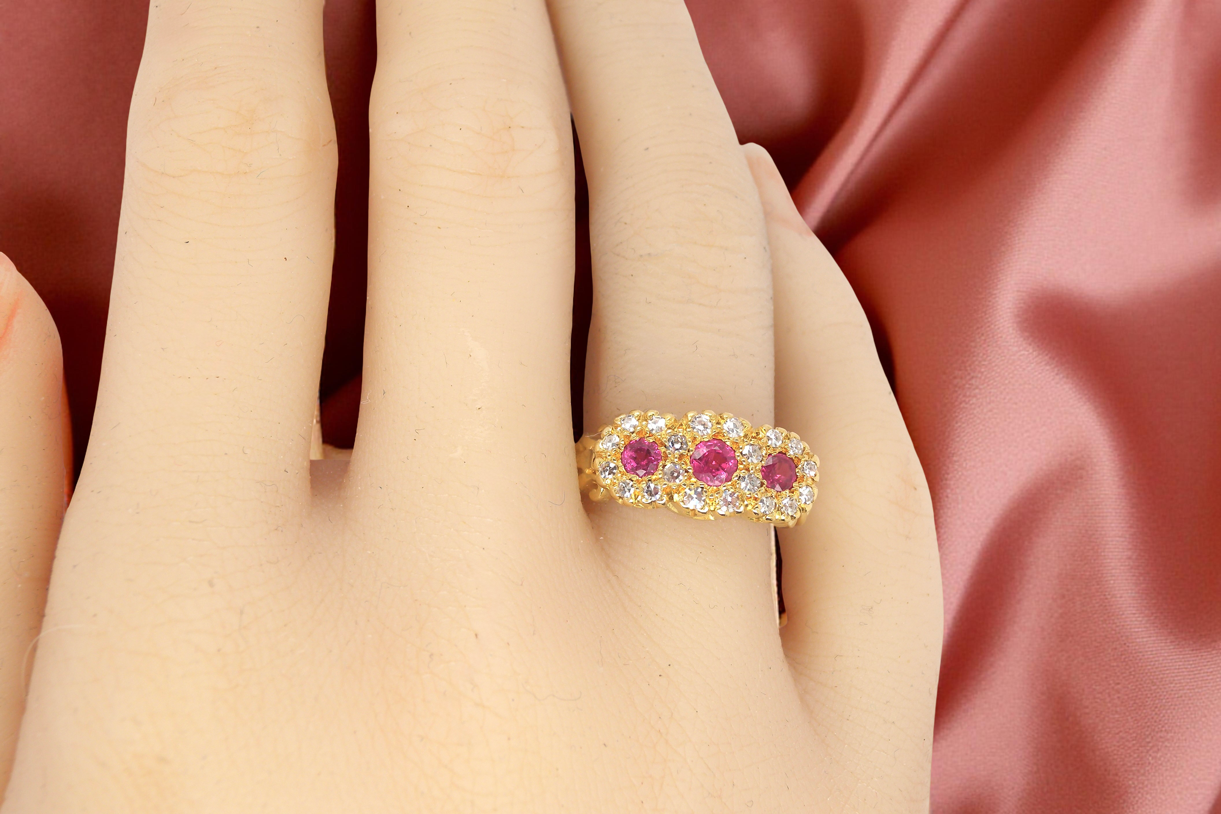 Gold ring with pink gemstones on a hand against a pink satin background