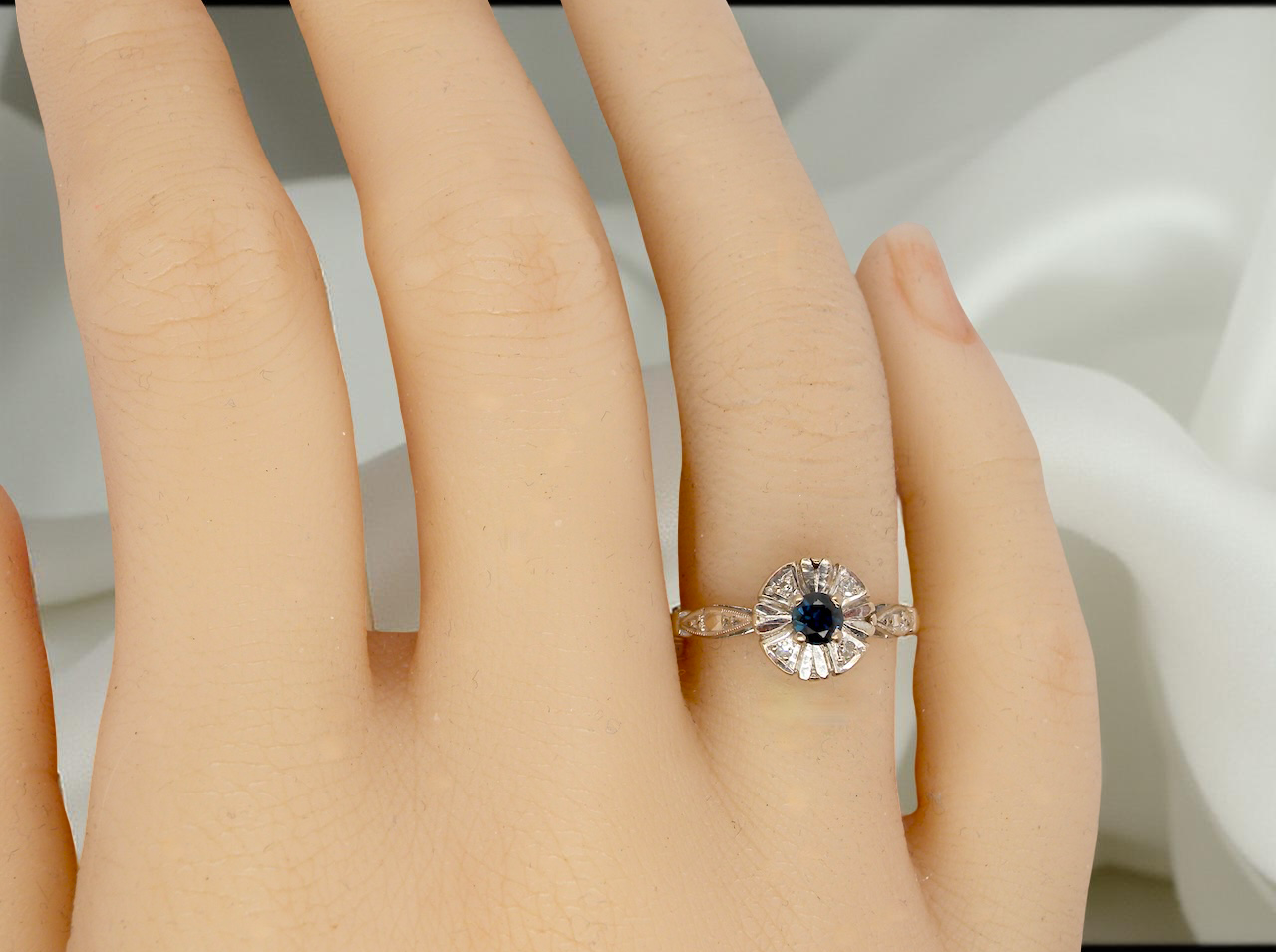 hand A vintage cluster ring featuring a deep black-blue sapphire