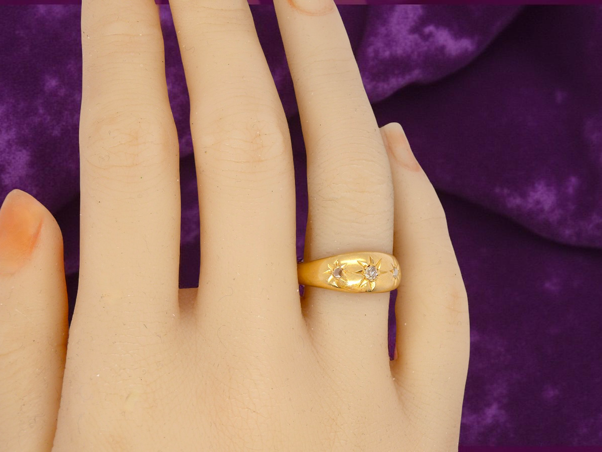 Gold ring on a hand with a purple fabric background