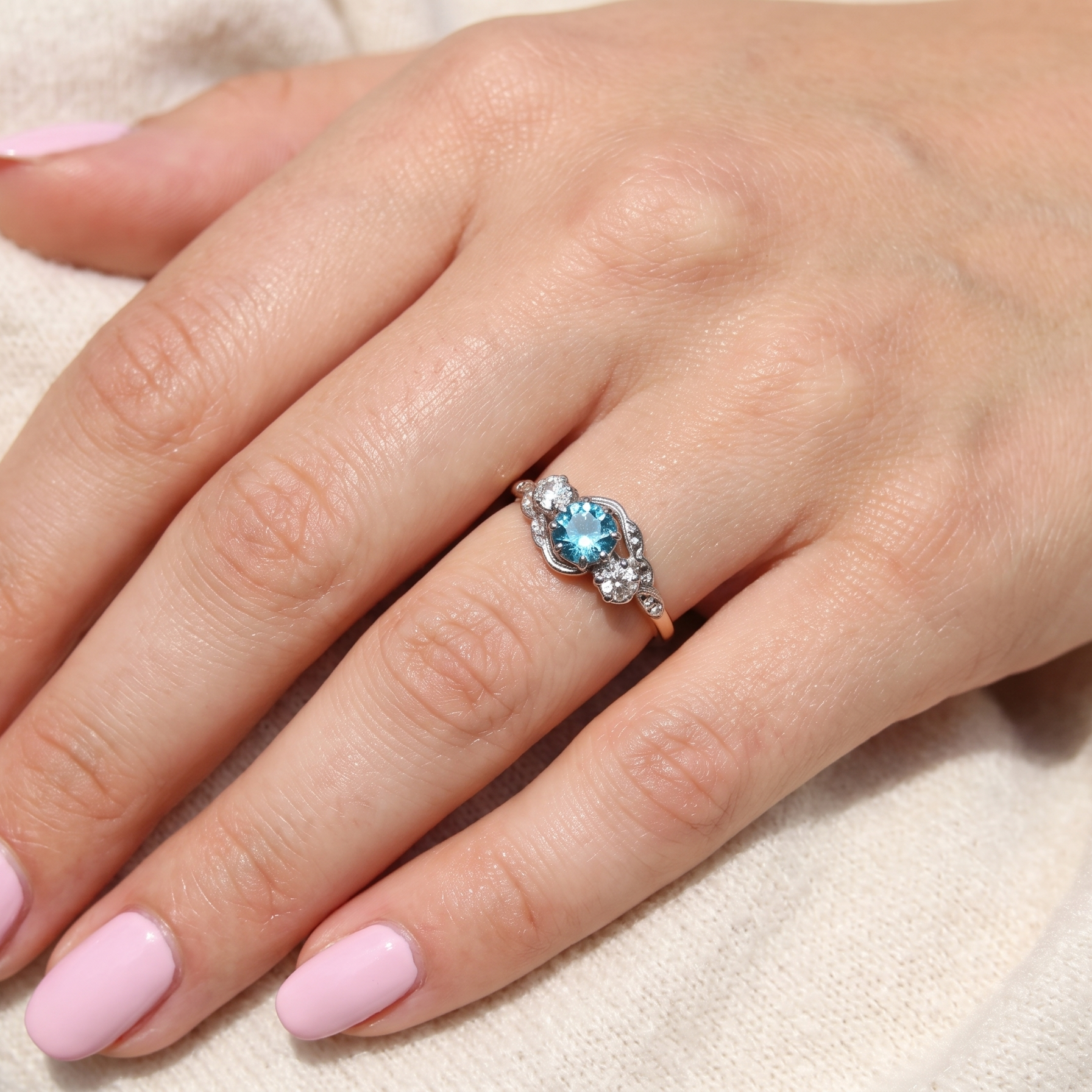 hand A vintage three stone ring, cross over style and features a round 6mm natural blue zircon centre stone