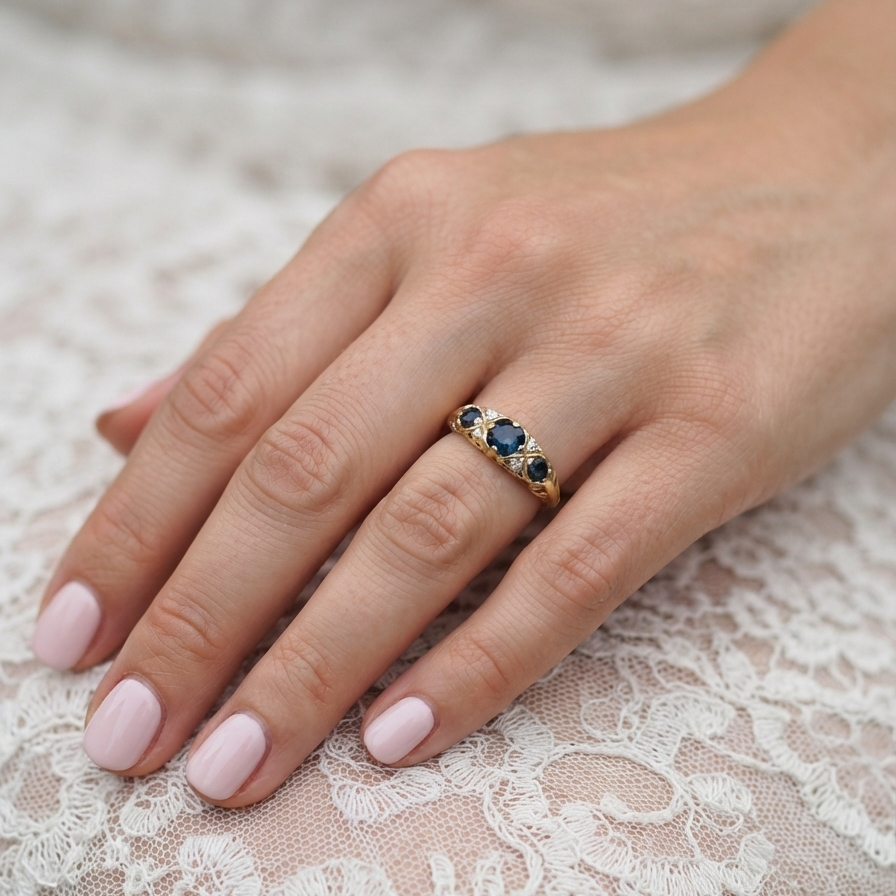 hand An 18 carat* boat shaped ring. Features three dark inky blue sapphires, centre 4.7mm, each end a 3mm stone.
