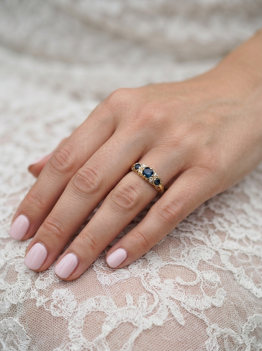 hand An 18 carat* boat shaped ring. Features three dark inky blue sapphires, centre 4.7mm, each end a 3mm stone.