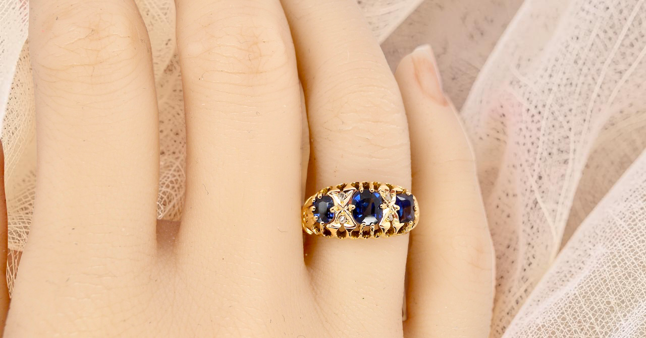 hand An 18 carat gold antique boat shaped ring. Features three oval to cushion cut sapphires, centre 6x5mm, each end 5x3mm. Mid to dark blue
