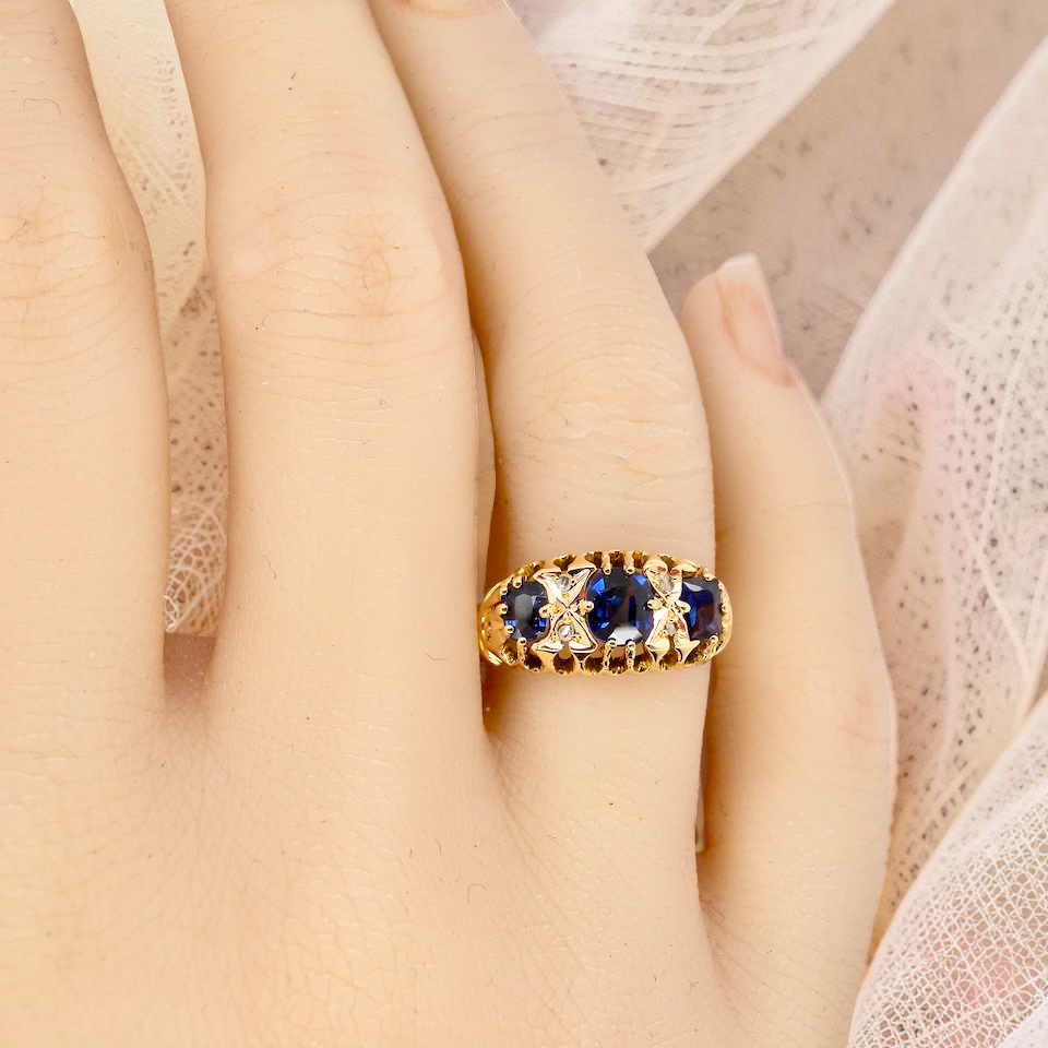 hand An 18 carat gold antique boat shaped ring. Features three oval to cushion cut sapphires, centre 6x5mm, each end 5x3mm. Mid to dark blue
