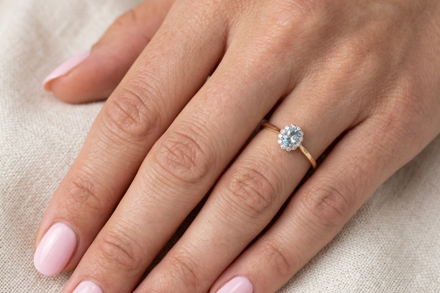 hand An 18 carat gold cluster ring. Set to the centre a lovely ice blue aquamarine 6x4mm, claw set.