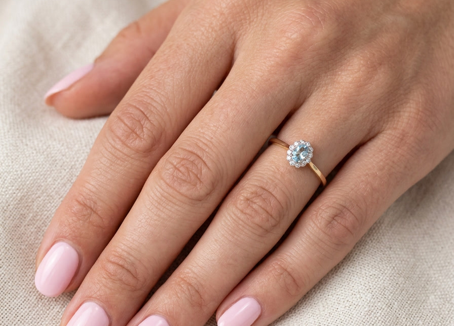 hand An 18 carat gold cluster ring. Set to the centre a lovely ice blue aquamarine 6x4mm, claw set.