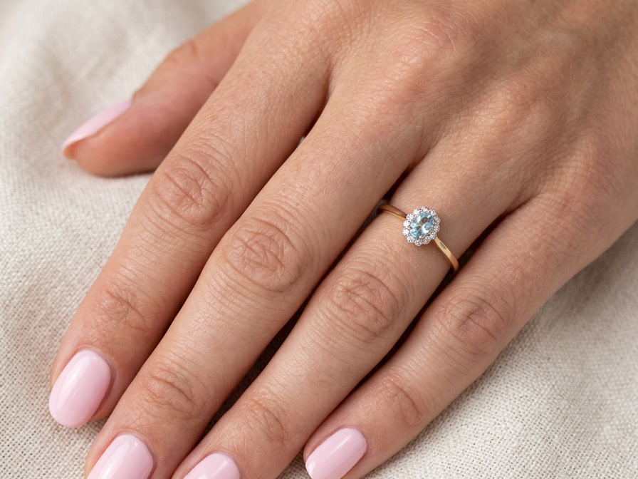 hand An 18 carat gold cluster ring. Set to the centre a lovely ice blue aquamarine 6x4mm, claw set.