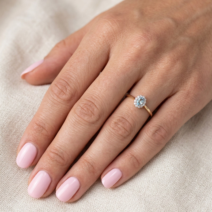 hand An 18 carat gold cluster ring. Set to the centre a lovely ice blue aquamarine 6x4mm, claw set.