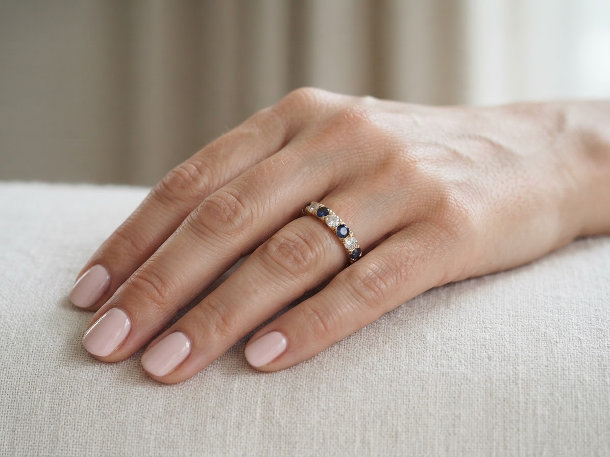 hand An 18 carat gold half hoop eternity ring. Set with four sapphires each 3.4mm (0.15 carats) and three diamonds, brilliant cut, 3.4mm (0.15 carats).