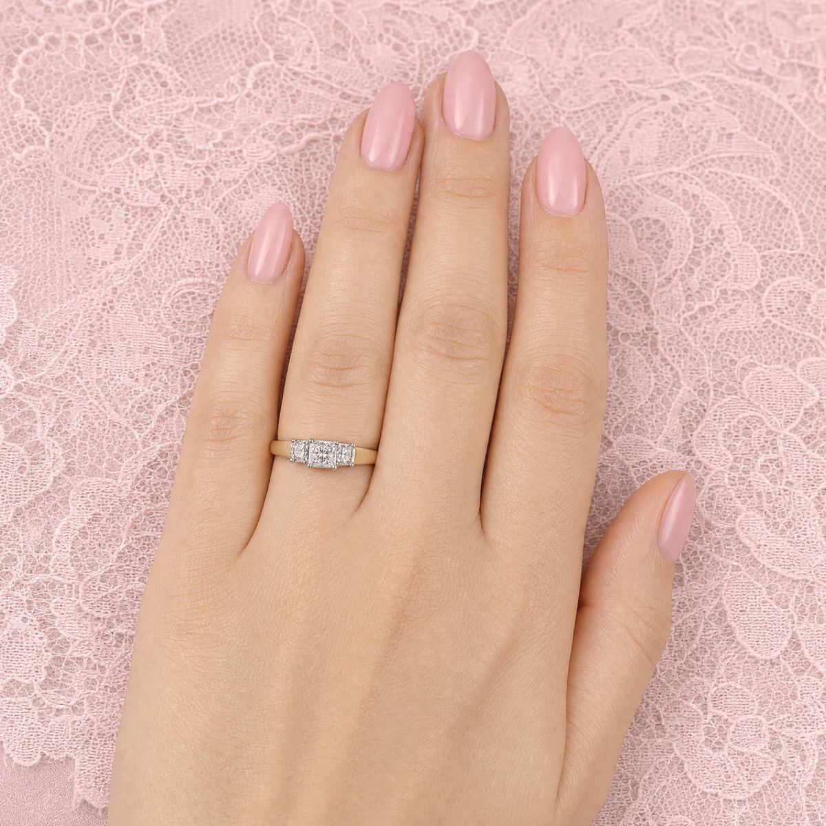 hand An 18 carat gold trilogy ring. Set with a total of twelve Princessa cut white diamonds, the centre portion measures 5x5mm, each side a 4.5x4.5mm setting,