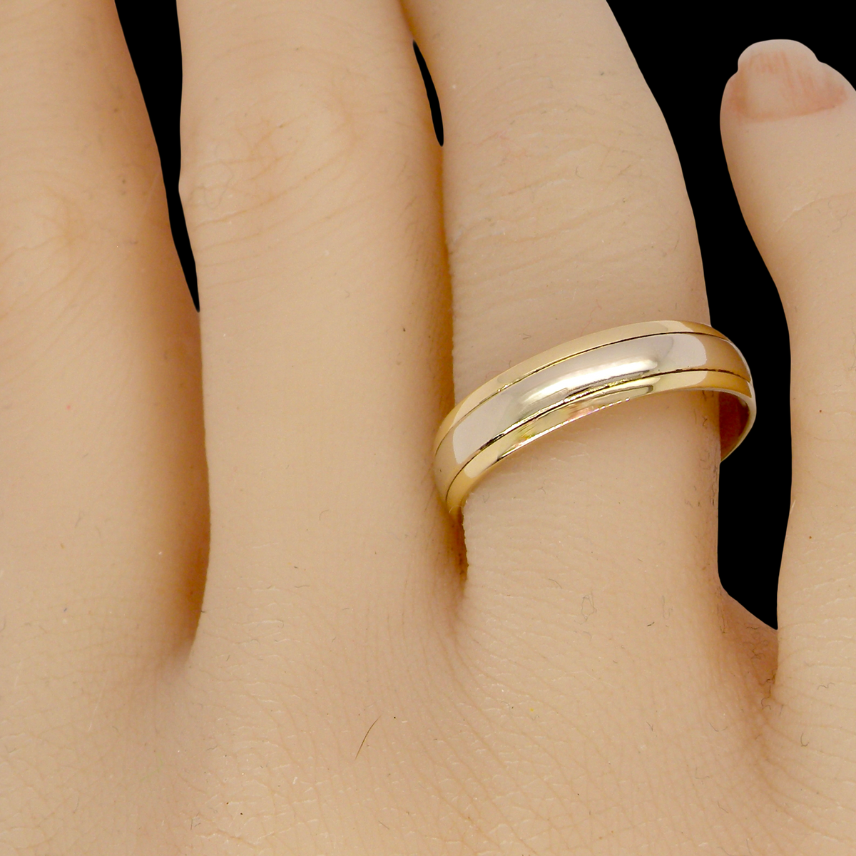 hand An 18 carat gold wedding ring. The inner band is white gold measures 3.5mm, and yellow gold narrower bands to each edge. Total width 4.75mm.