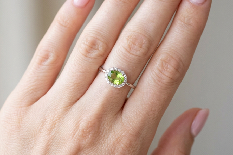 hand An 18 carat white gold* cluster ring. Features and oval shaped peridot gemstone, measures 8.5x6.5mm.