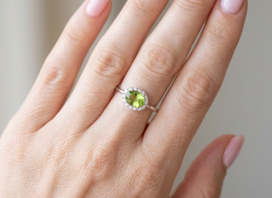 hand An 18 carat white gold* cluster ring. Features and oval shaped peridot gemstone, measures 8.5x6.5mm.