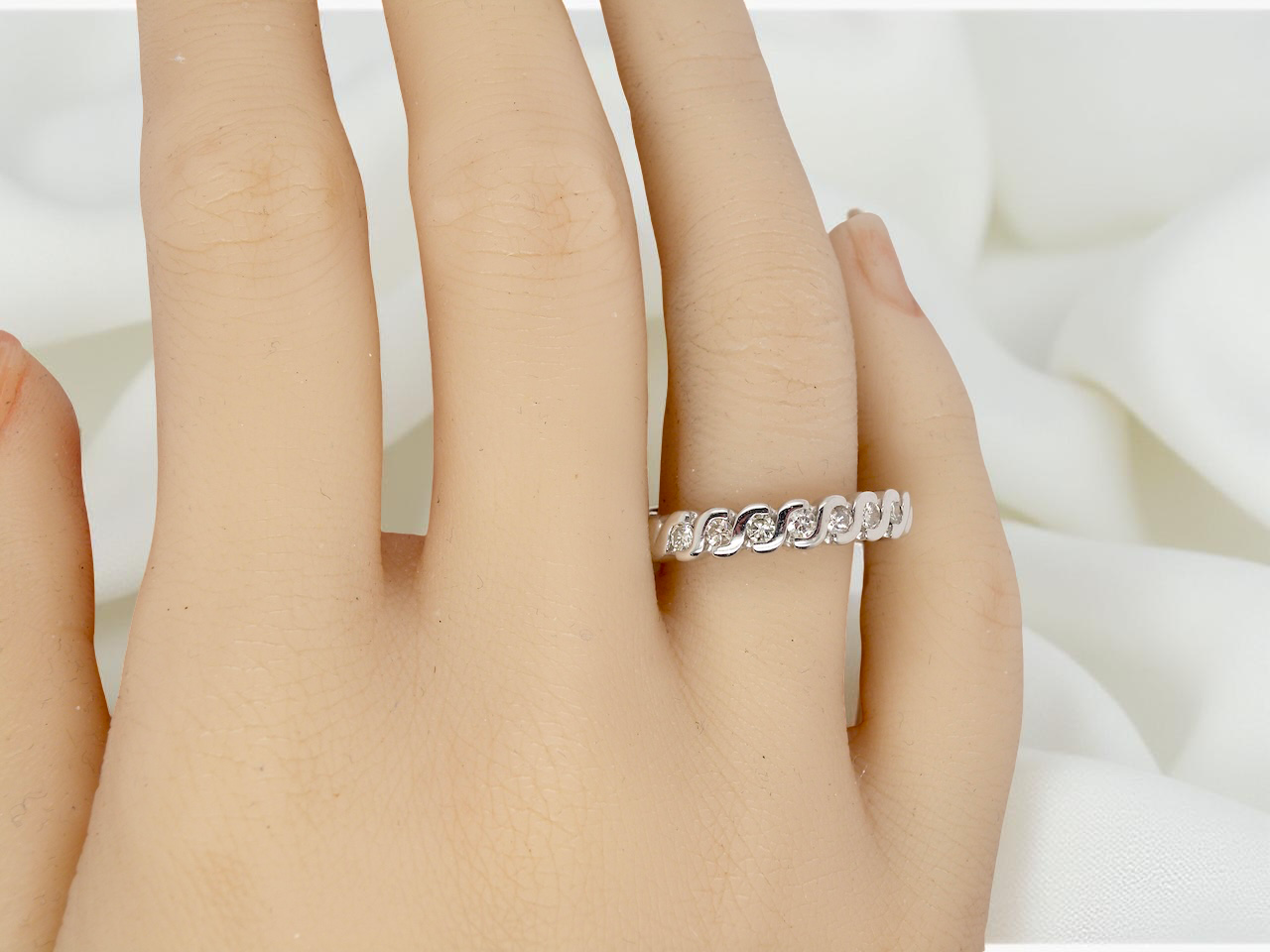 hand An 18 carat white gold half hoop eternity ring. Set with seven brilliant cut white diamonds,