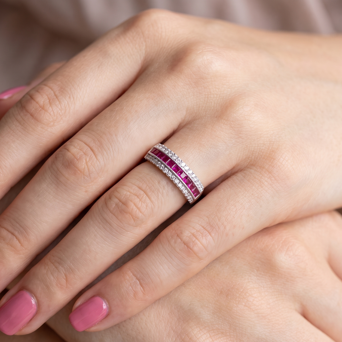 hand An 18 carat white gold half hoop ring. A triple row design with a line of channel set calibre cut rubies running along the centre , to a total carat weight of 0.97 carats.