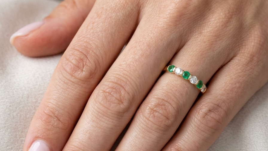 hand An 18 carat yellow gold half hoop eternity ring. Set with four bright green emeralds, each 3mm diameter (est each 0.10 carats) .