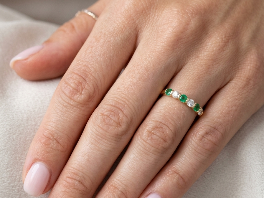 hand An 18 carat yellow gold half hoop eternity ring. Set with four bright green emeralds, each 3mm diameter (est each 0.10 carats) .