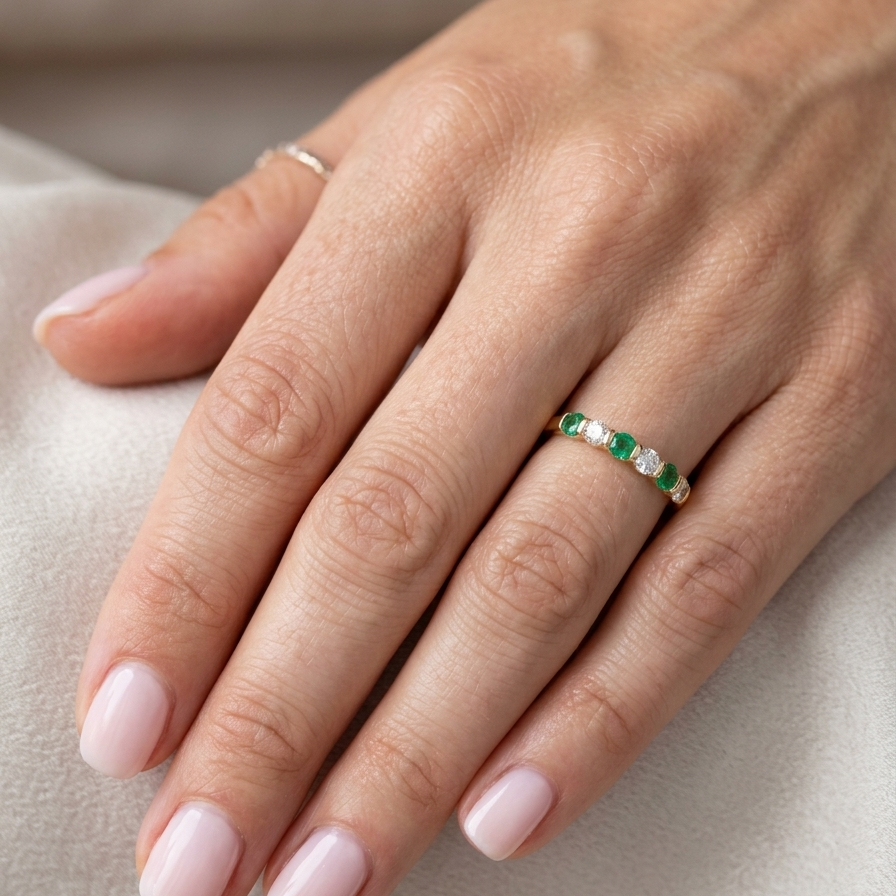 hand An 18 carat yellow gold half hoop eternity ring. Set with four bright green emeralds, each 3mm diameter (est each 0.10 carats) .
