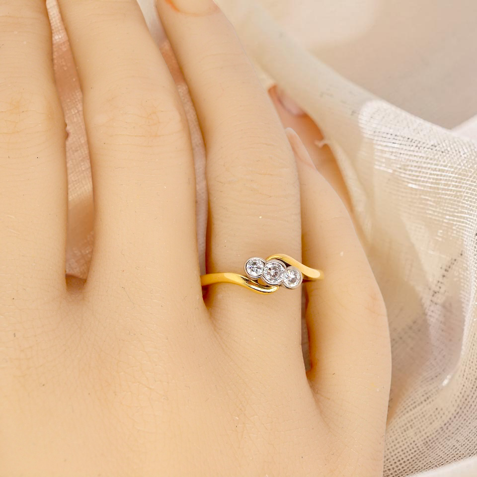 hand An 18 carat yellow gold three stone ring, cross over style, and set with brilliant cut white diamonds.
Centre stone 3mm (0.10 carats)