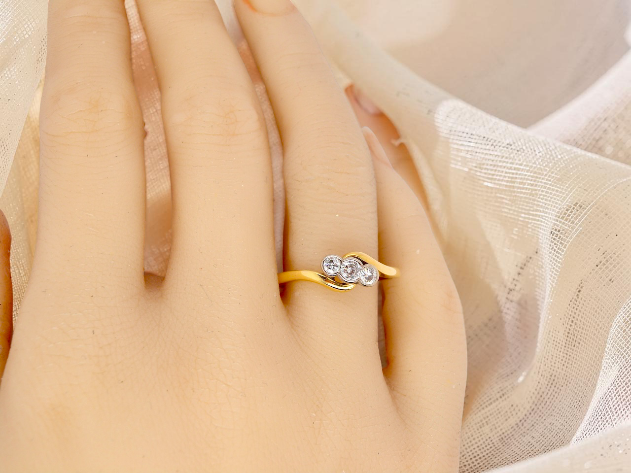 hand An 18 carat yellow gold three stone ring, cross over style, and set with brilliant cut white diamonds.
Centre stone 3mm (0.10 carats)