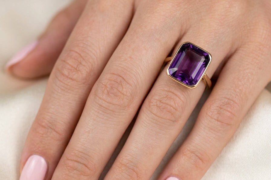 hand An antique dress ring that features a rectangular cut amethyst. Very dark purple, measures 12x10mm. Rim setting.