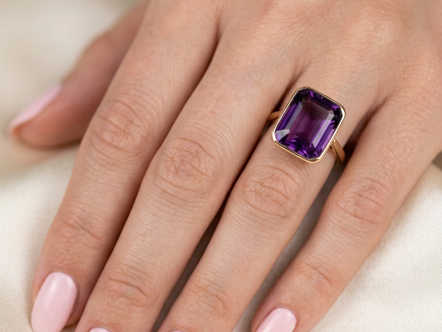 hand An antique dress ring that features a rectangular cut amethyst. Very dark purple, measures 12x10mm. Rim setting.