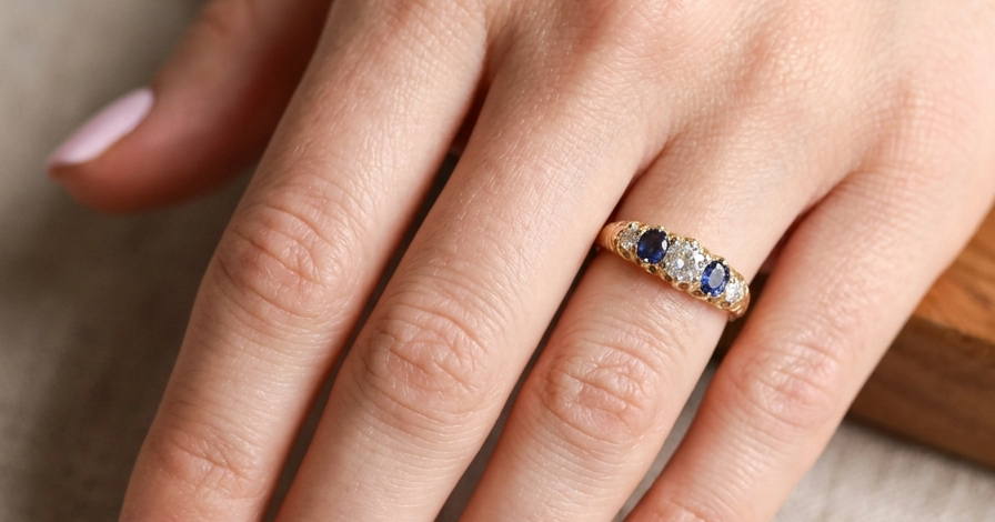 hand An antique ring from the early years of the 20th century. Centre stone 5mm diameter (0.50 carats) Colour H-j, clarity Si. Each side a mid colour blue sapphire 4mm diameter.