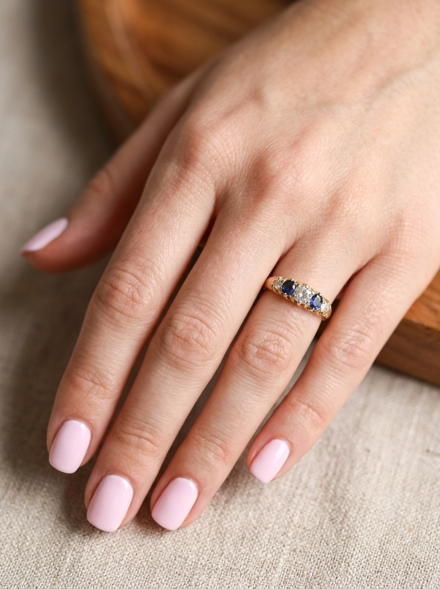 hand An antique ring from the early years of the 20th century. Centre stone 5mm diameter (0.50 carats) Colour H-j, clarity Si. Each side a mid colour blue sapphire 4mm diameter.