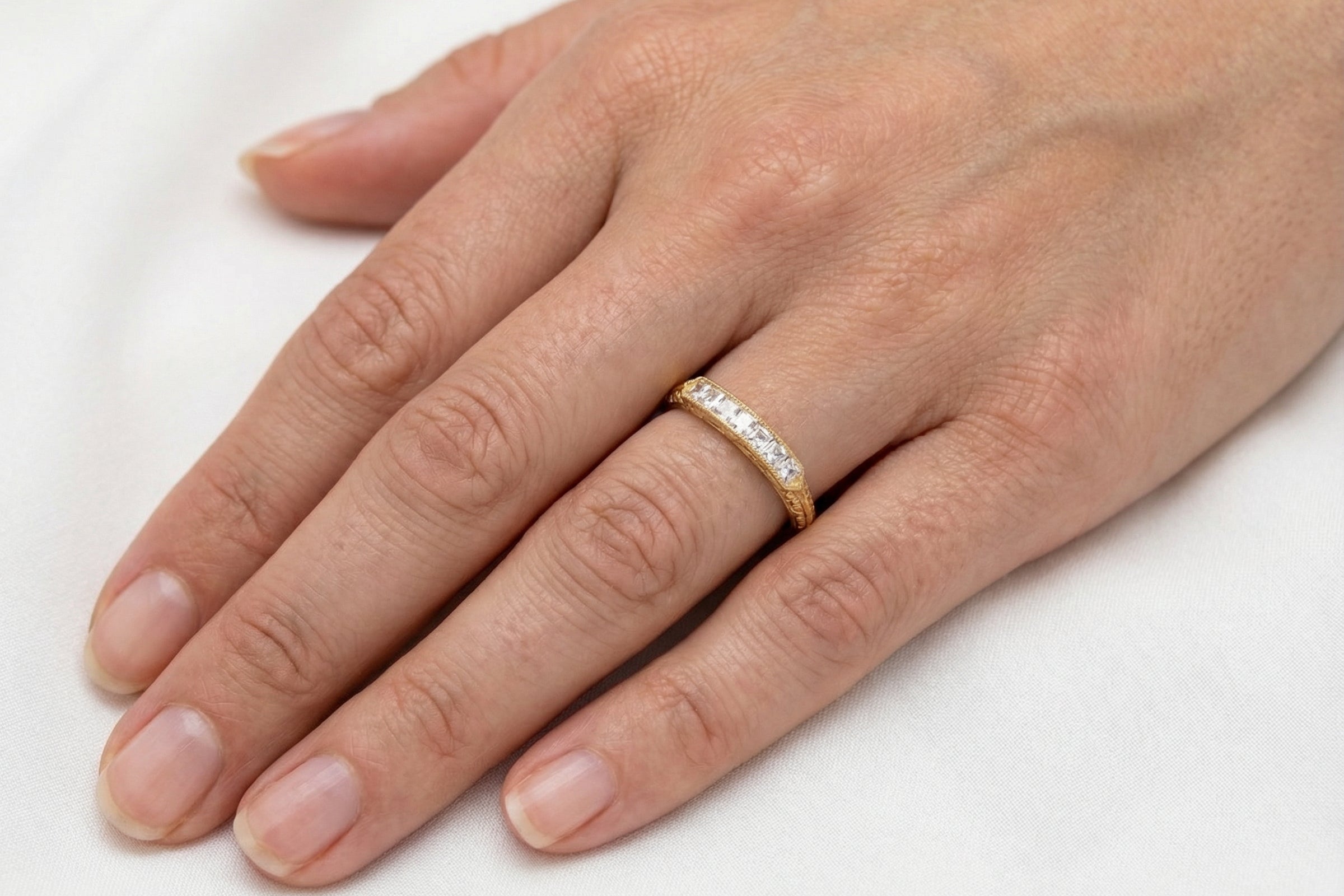 hand An attractive half hoop diamond eternity ring. Set with six step cut white diamonds, that sit side by side, the colour estimated at H-i, clarity Si.