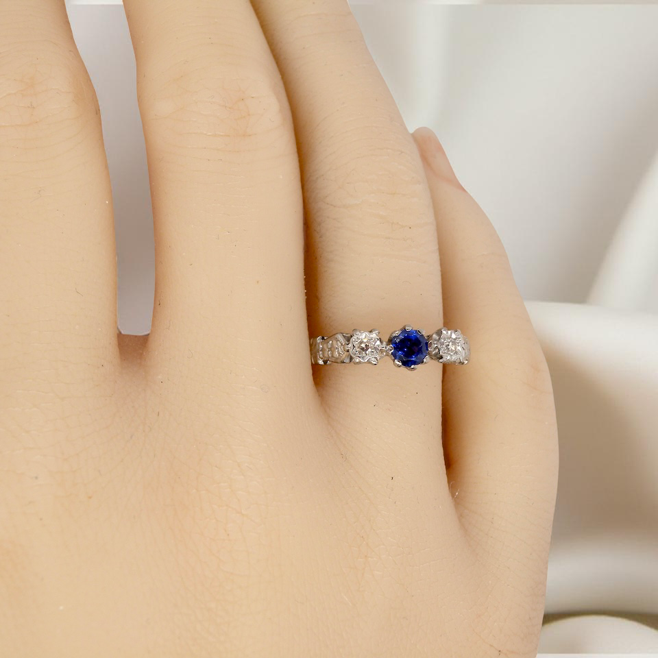 hand An early 20th century engagement ring. The centre stone a dark blue sapphire